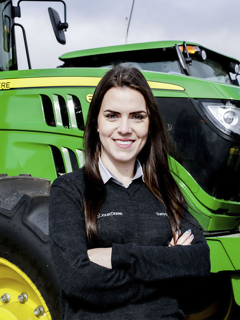 foto mostrando funcionario de braços cruzados com trator John Deere atras