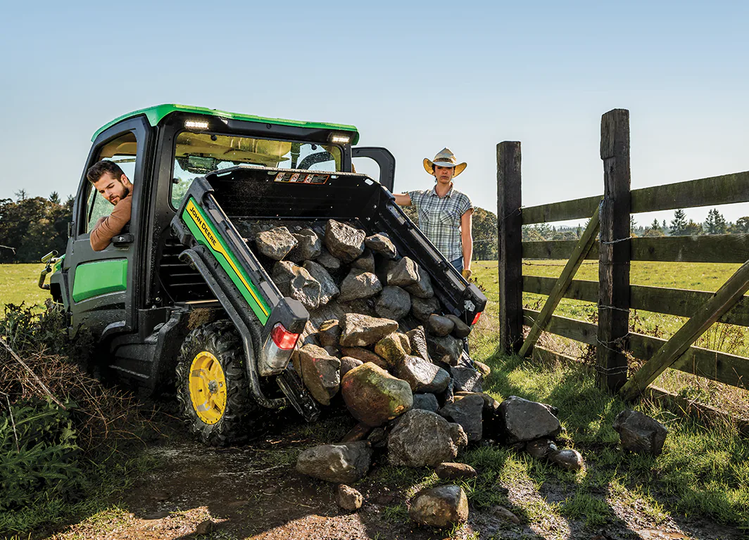 utilitario gator John Deere descarregando pedras